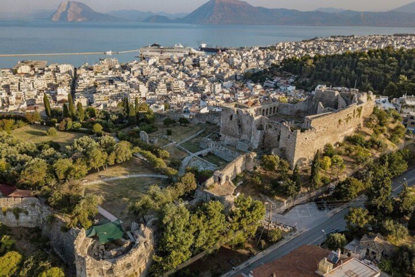 An aerial view of a historic city with a prominent castle, a large body of water, and a mountainous backdrop. 2