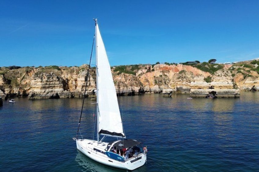 A sailboat on calm waters with a rocky coastline in the background. 5