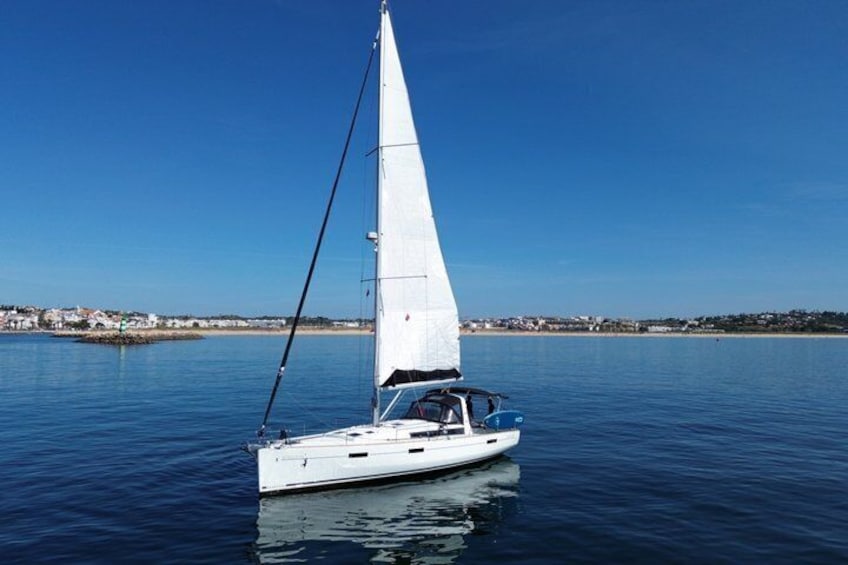 A sailboat on calm water with a clear sky and a distant shoreline. 2