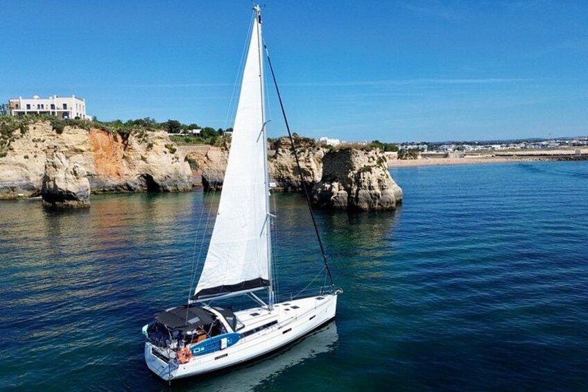 Un velero en aguas tranquilas cerca de acantilados rocosos y un edificio. 2