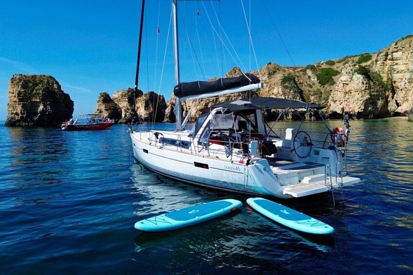 Un velero con dos pontones azules amarrado cerca de acantilados rocosos. 3