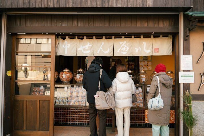 Een winkelgevel met een bord in Japanse karakters, houten deuren en verschillende etalageartikelen. 2