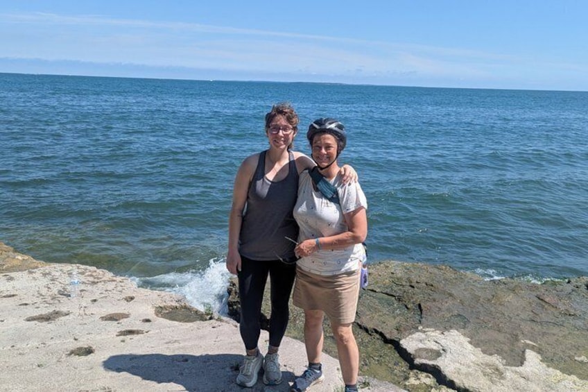Deux personnes se tiennent sur une côte rocheuse, avec la mer en arrière-plan. 5