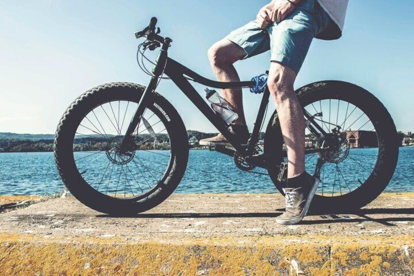Une personne debout à côté d’un vélo, près d’une promenade au bord de l’eau. 1