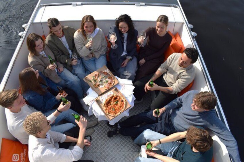 A group of people on a boat with pizza boxes and drinks. 2