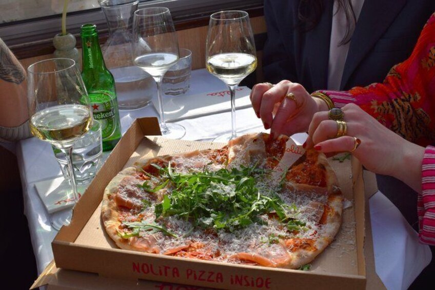 A person cutting a pizza with a box labeled 'NOLITA PIZZA INSIDE.' 5