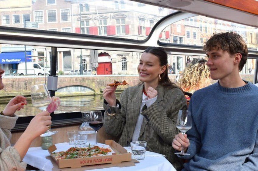 Mensen eten op een boot, met een pizzadoos waarop staat 'Nolita Pizza Inside'. 5