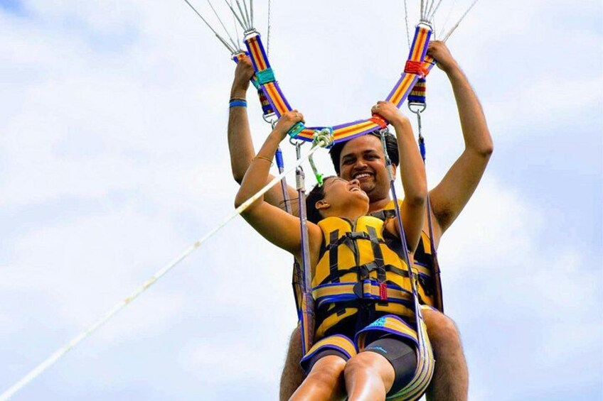 A person in a harness attached to a parachute system, with another person assisting. 1