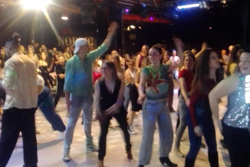 A group of people dancing in a crowded indoor space. 3