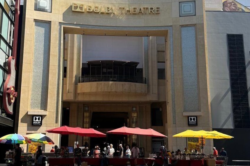 The exterior of the Dolby Theatre with red and yellow umbrellas and people outside. 4