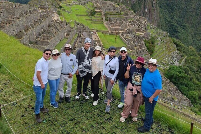A group of people standing on a grassy hill overlooking ancient ruins. 3