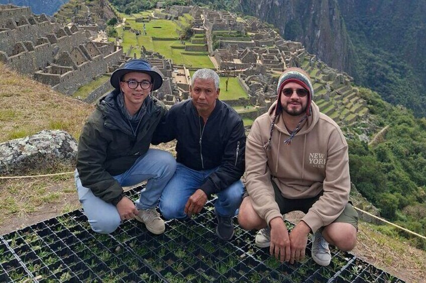 Three people sitting on a metal grid with Machu Picchu in the background. 5