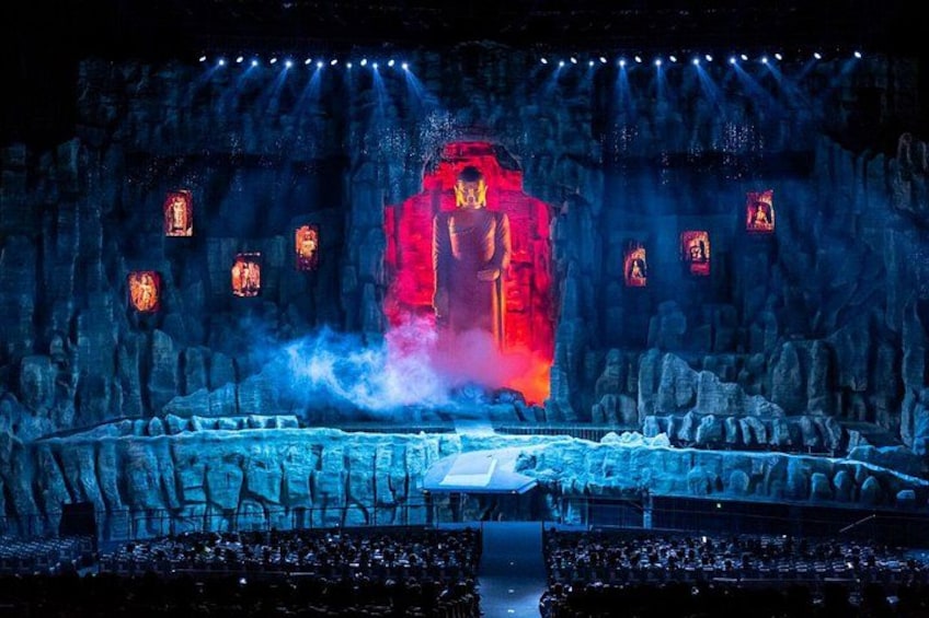 A stage with a rock formation backdrop, illuminated by spotlights and featuring a central red-lit structure. 1