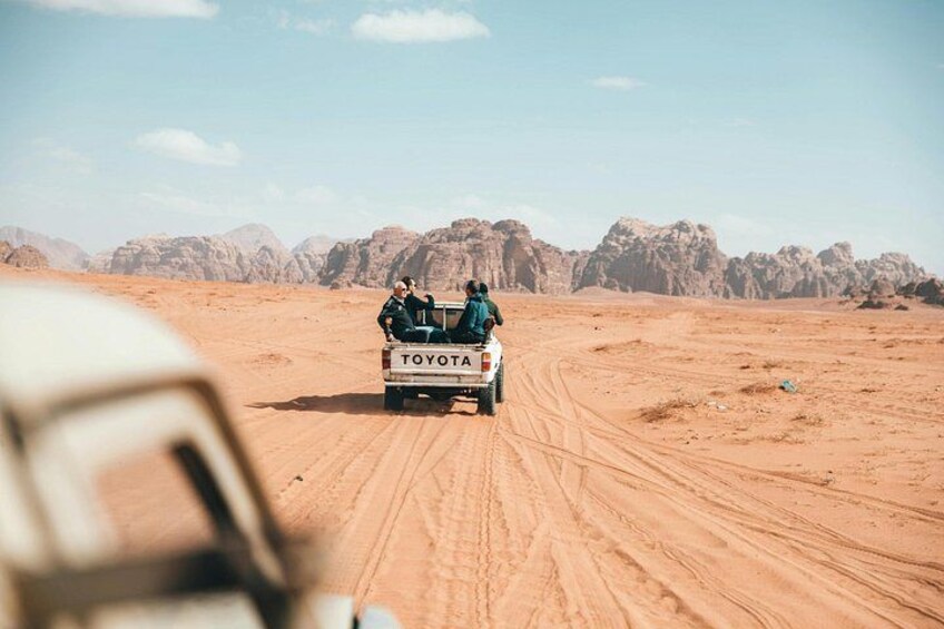 Un véhicule tout-terrain Toyota sur une route de terre dans un désert, avec des montagnes rocheuses en arrière-plan. 2