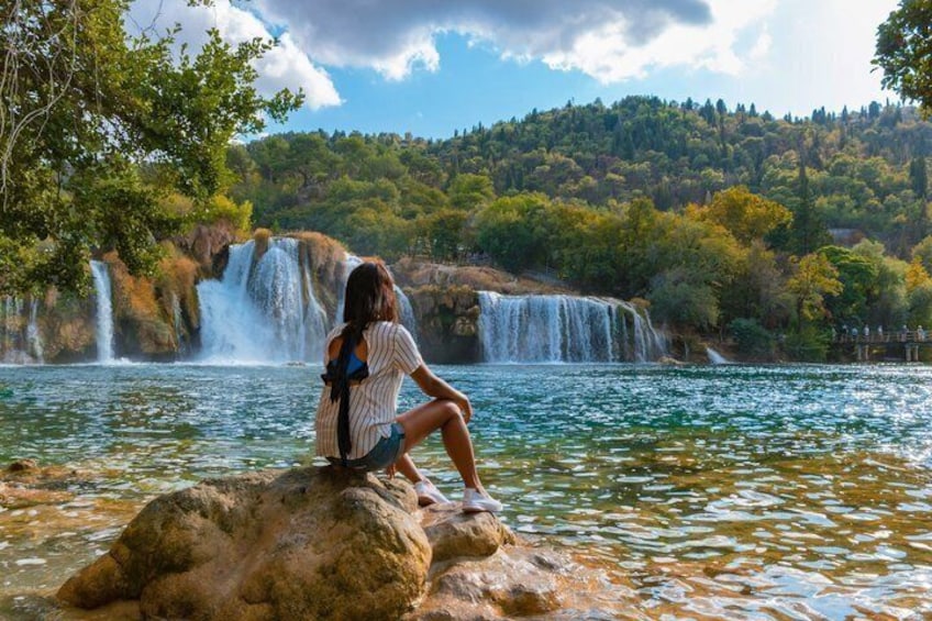A person sitting on a rock by a waterfall. 2