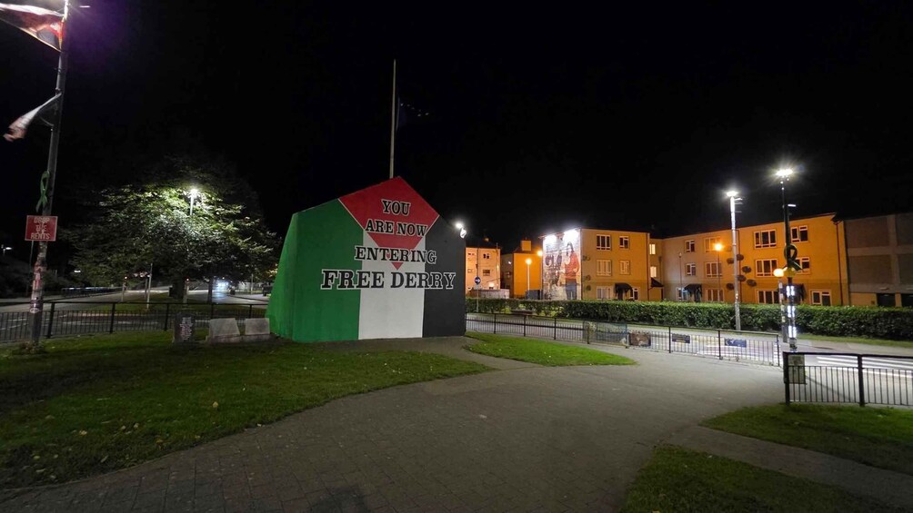 Yöllä valaistu opastekyltti, joka osoittaa tien Free Derryyn, ja jossa on käytetty punaista, valkoista ja vihreää väriä. 4