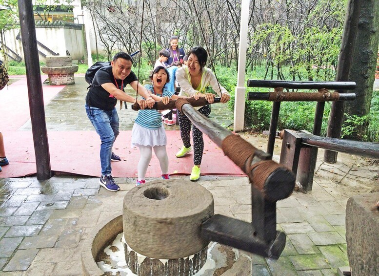 A group of people using a traditional hand-cranked water pump. 3