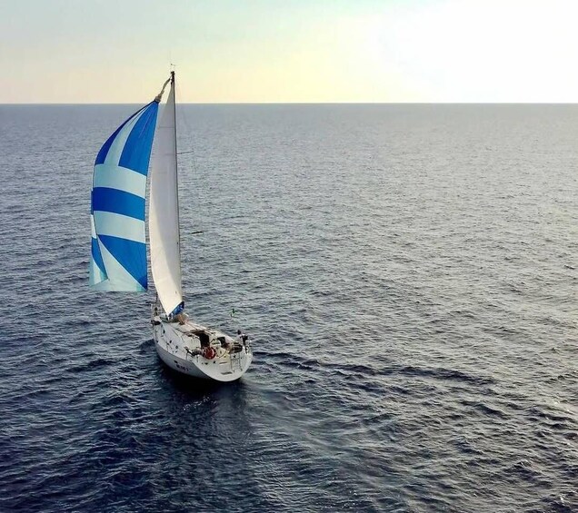 A sailboat with a blue and white sail on a calm sea. 3