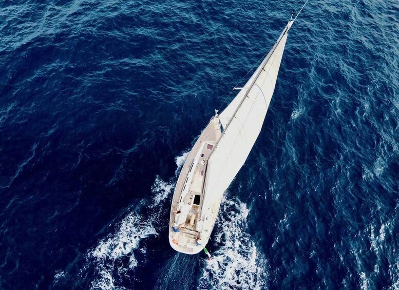 A sailboat with a white hull and a large sail, sailing on a deep blue ocean. 4