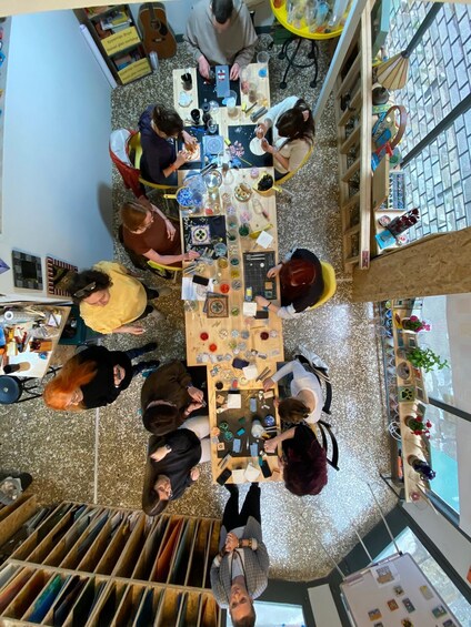 A group of people engaged in a craft activity around a table with various materials and tools. 5