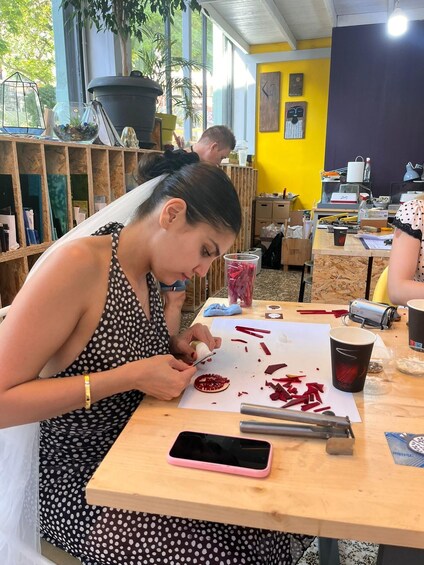 A person cutting red material on a wooden table in a workshop with yellow walls and wooden shelves. 4