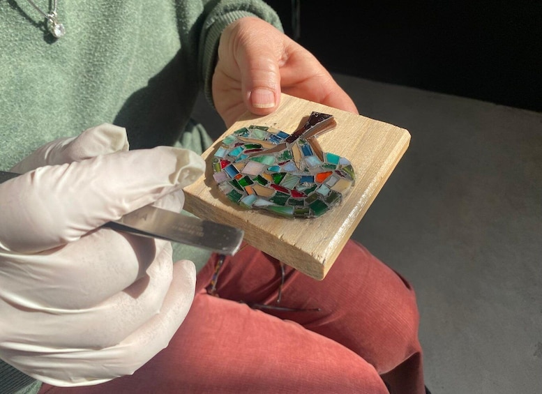 A person holding a mosaic piece with a knife. 1