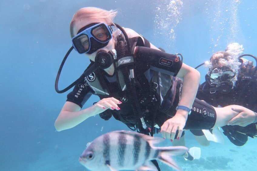 Two scuba divers underwater with a fish nearby. 4