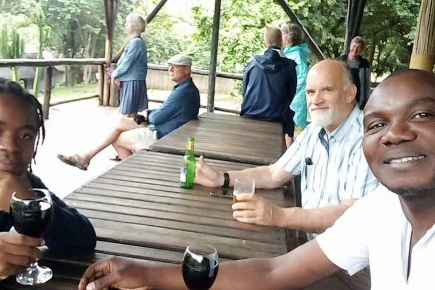 People sitting at a wooden table outdoors, with drinks and a green bottle on the table. 3