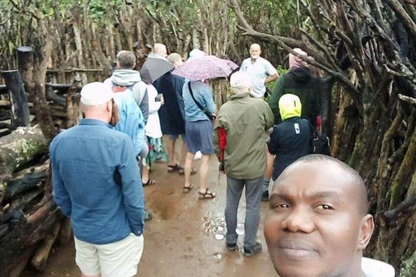 A group of people walking through a forested area with a muddy path. 2