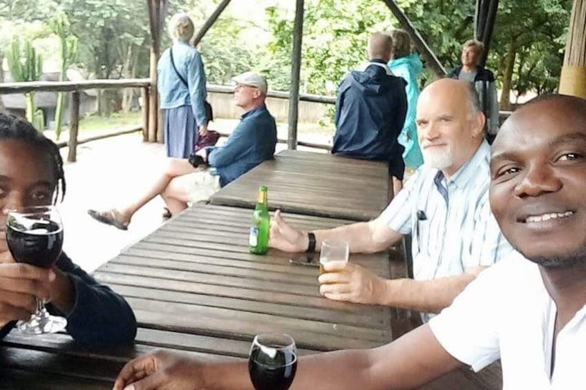 People sitting at a wooden table outdoors, holding drinks. 4