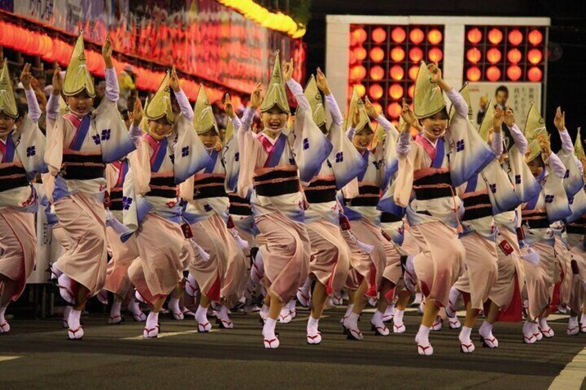 A group of dancers in traditional attire performing on a stage with a backdrop of red lanterns. 4