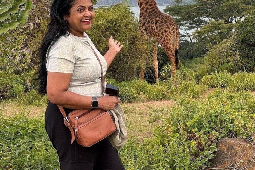 A person standing with a giraffe in a natural setting. 1