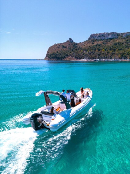 A boat with people on a turquoise sea, a rocky coastline, and a clear sky. 1