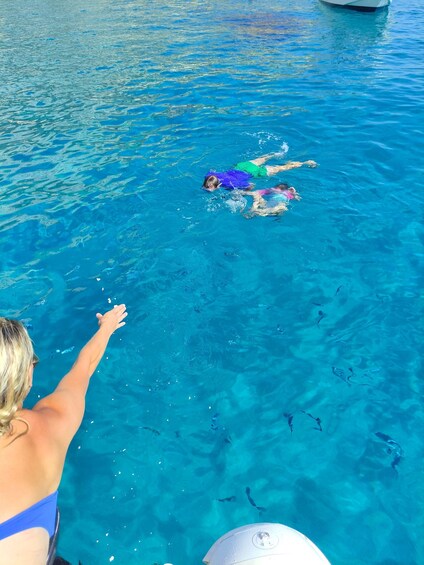 A person swimming in a clear blue pool with another swimmer in the background. 4