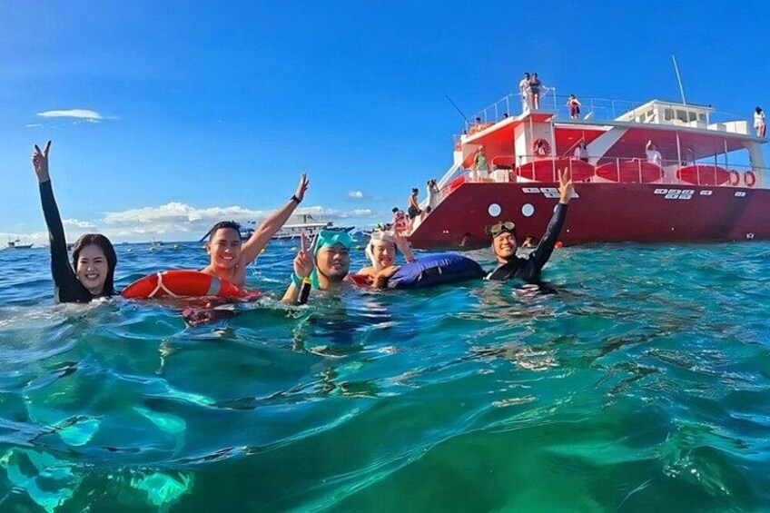 People swimming in the ocean with a red boat in the background. 1