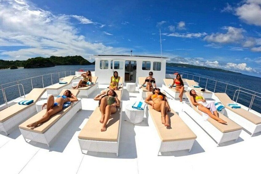 A boat with people sunbathing on deck chairs. 2