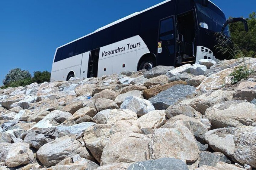 A tour bus parked on a rocky slope. 2