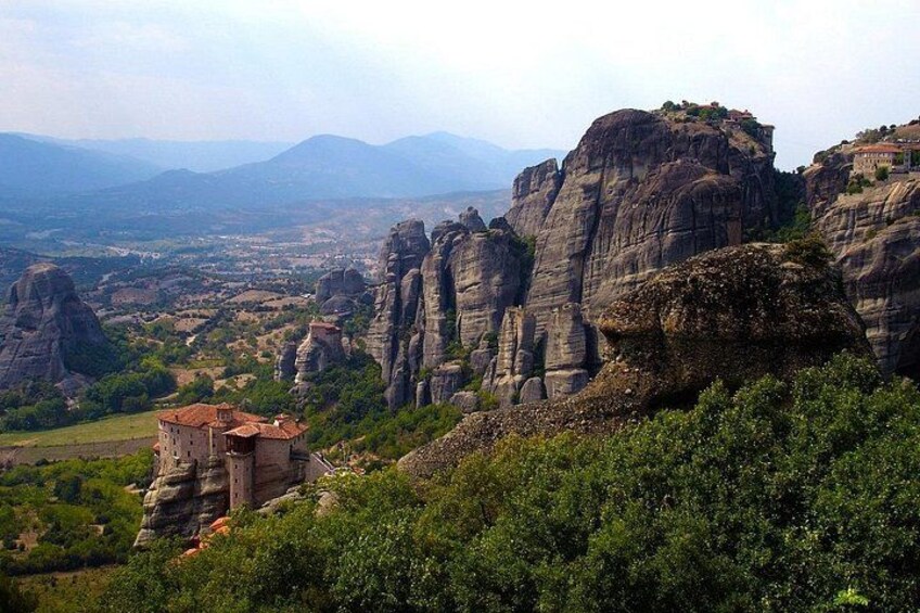A rocky landscape with a small building and a village in the valley. 1