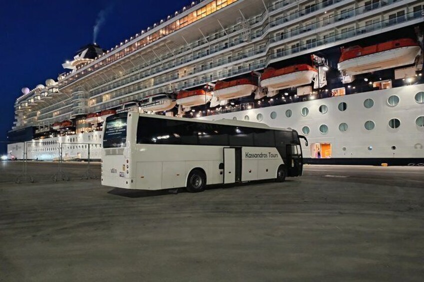 A white cruise ship docked at a port with a white tour bus labeled 'Kassandros Tours' in front. 4