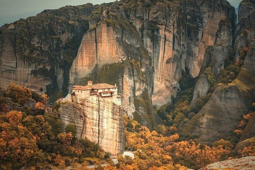 A monastery perched on a cliff, surrounded by rocky terrain and autumn foliage. 5