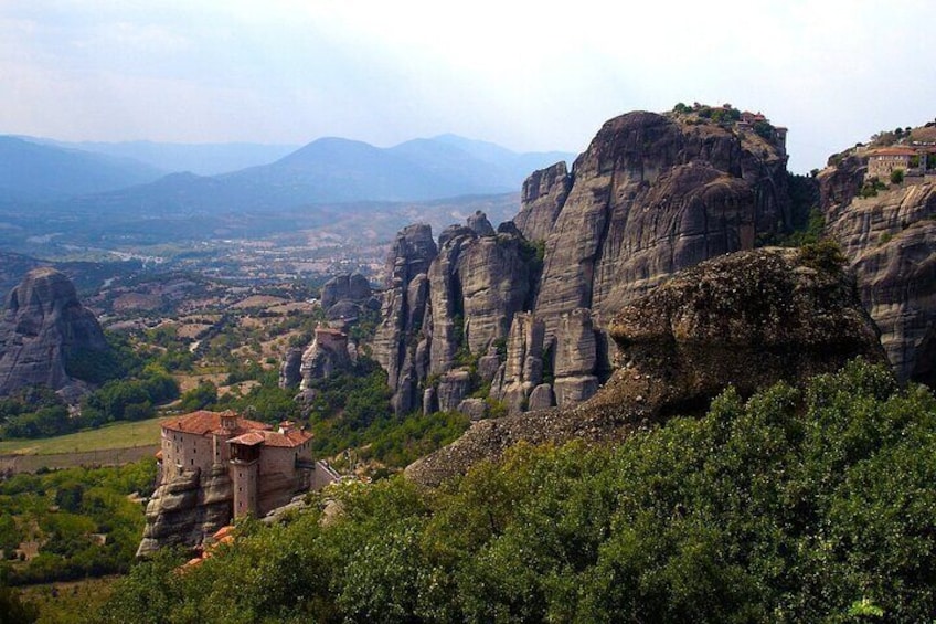 A mountainous landscape with rock formations and a small building. 1