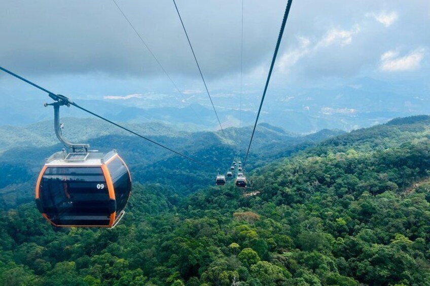 A cable car system with cabins numbered 09 and 10, suspended over a dense forested mountain range. 3