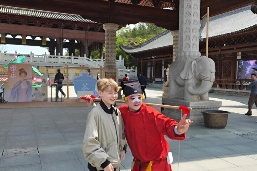 Two individuals in traditional attire, a stone elephant statue, and a traditional building with a tiled roof. 5