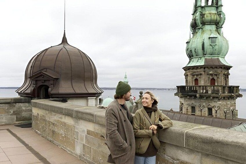 A couple standing by a historical building with a dome and a green spire. 2