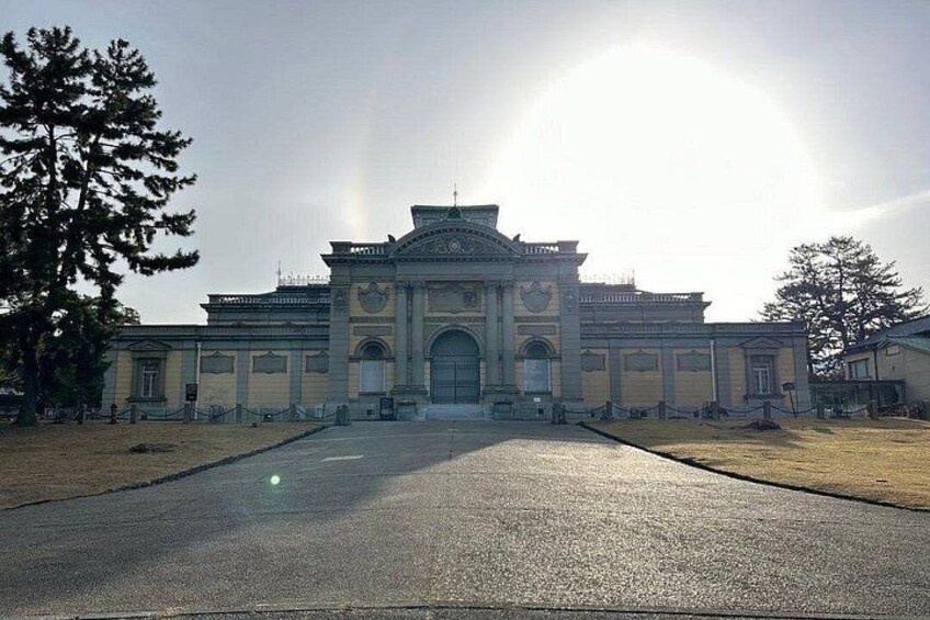 A large, historic building with a central archway, surrounded by a paved area and trees. 5