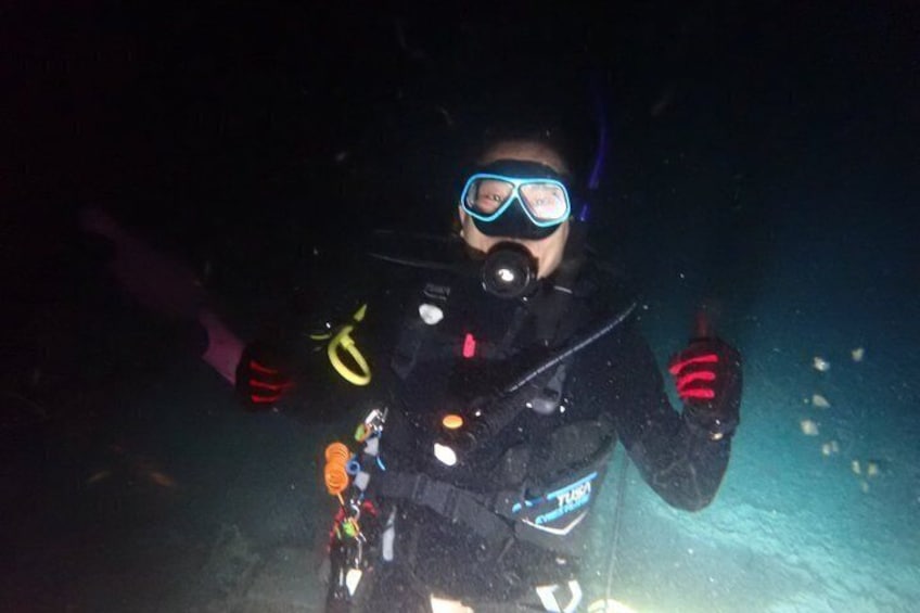 A person scuba diving underwater, wearing a black wetsuit, blue fins, and a snorkel. 5