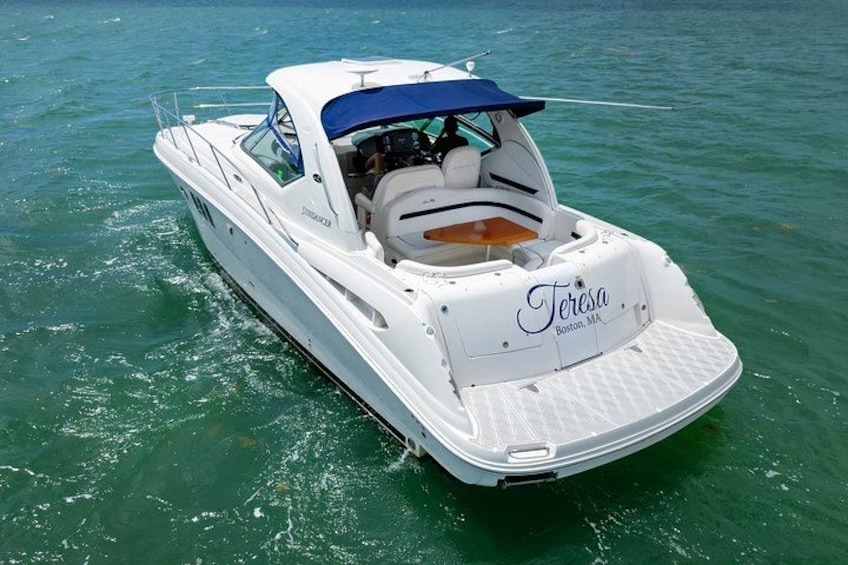 Un barco blanco llamado 'Teresa' con toldo azul, flotando sobre aguas tranquilas. 2