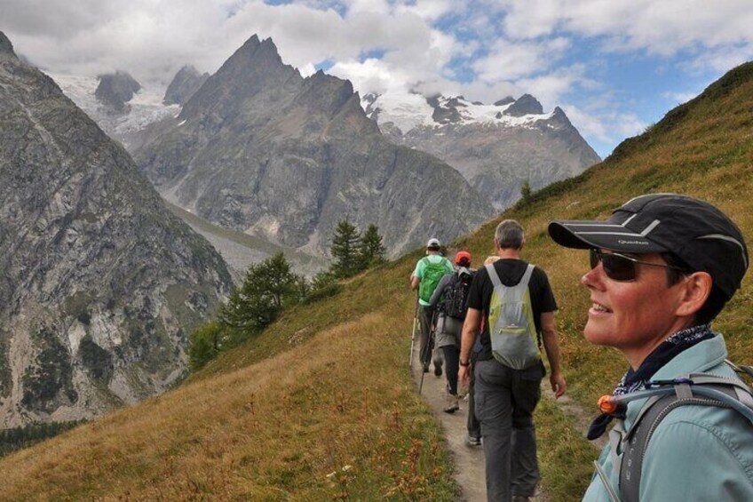 A group of hikers on a mountain trail with rugged terrain and snow-capped peaks in the background. 3