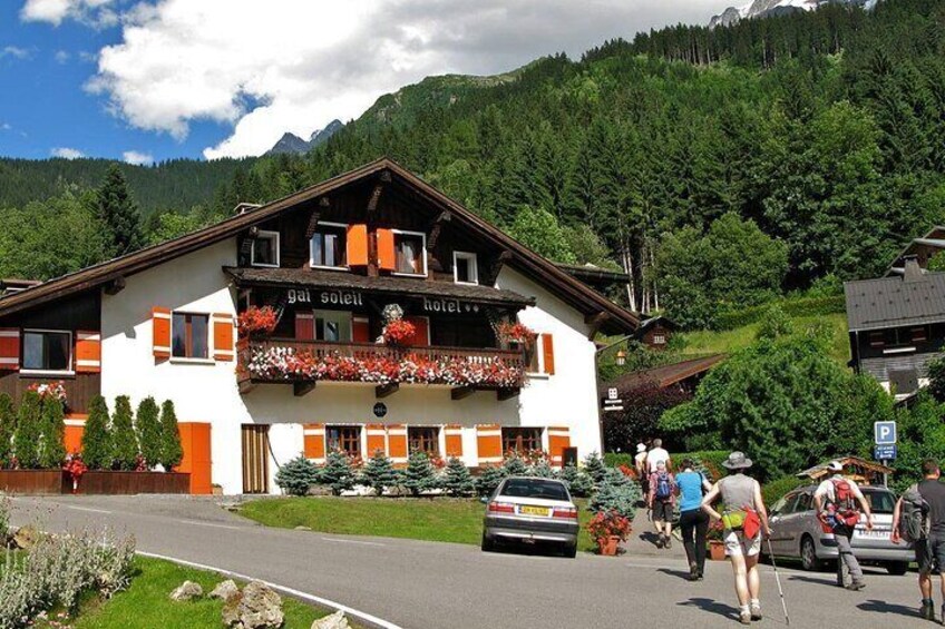 A mountain lodge with a balcony decorated with flowers, surrounded by lush greenery and a clear sky. 5