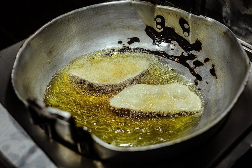 A frying pan with oil and two pieces of food being fried. 4